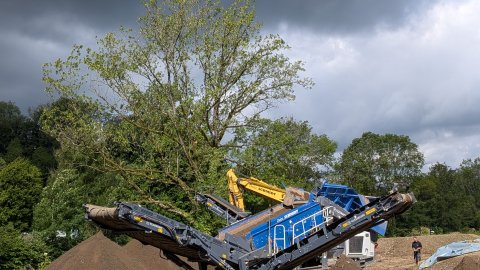 Maschinelle Trennung der obersten Bodenschicht mit der mobilen Raupensiebanlage in drei Fraktionen.